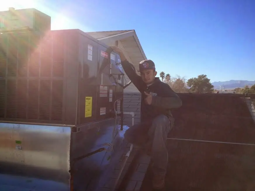 HVAC technician performing Heat Pump Repair on a rooftop unit in Monroe